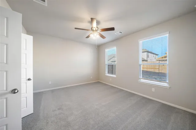 an empty room with windows and fan