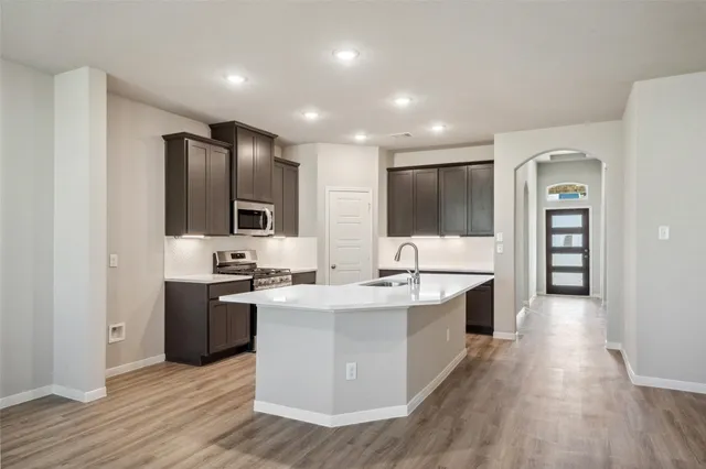 a large white kitchen with stainless steel appliances kitchen island granite countertop a stove and a sink