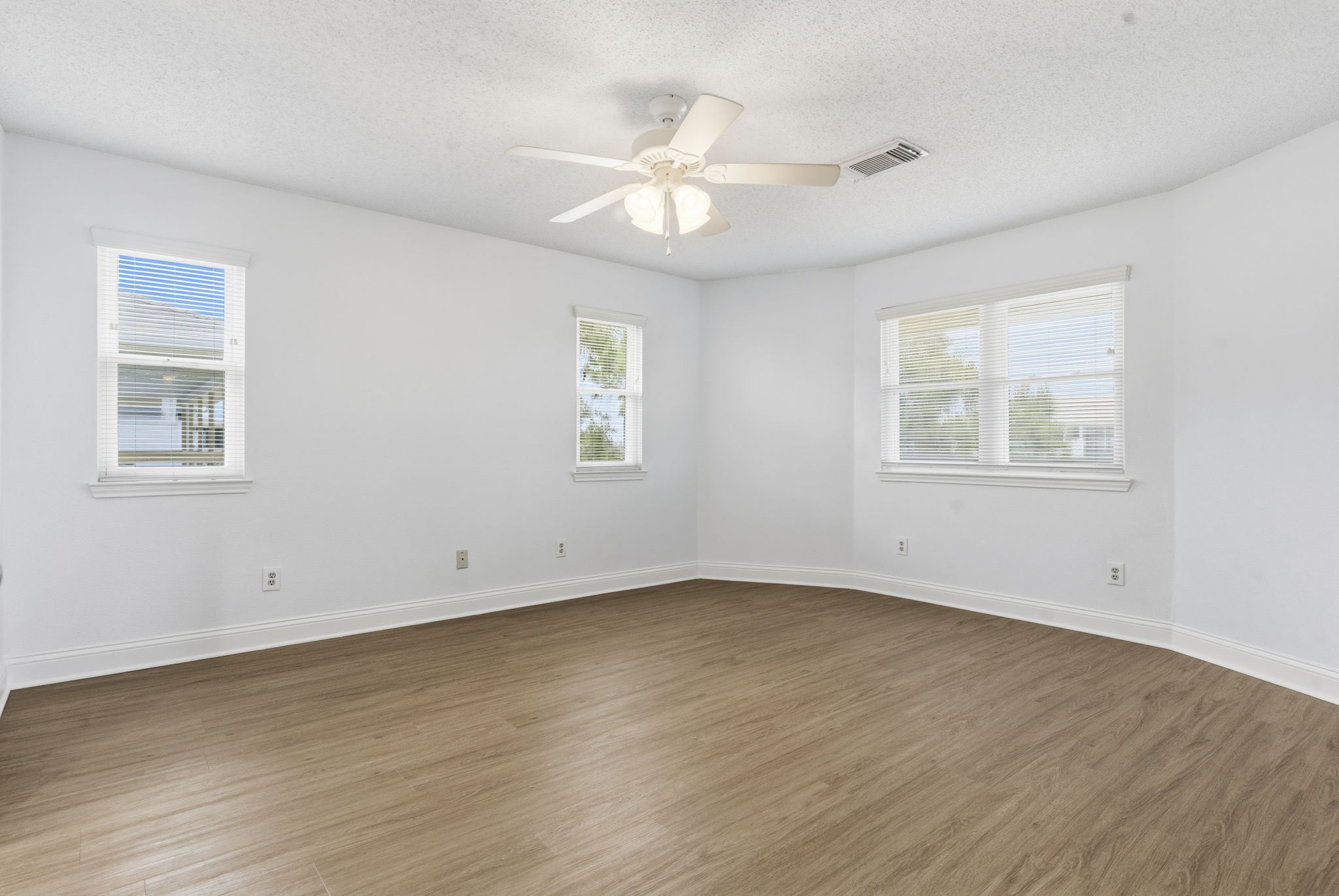 119 Sand Shoals Road Freeport, TX 77541 - Photo 20 of 34 Primary bedroom — corner-windowed bedroom with neutral walls, ceiling fan, and warm-tone wood-look flooring.