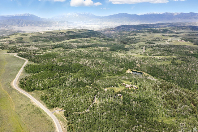 1555 North Wolf Creek Ranch Road, Unit 11 Heber City, UT 84036 - Photo 4 of 9 Expansive wooded landscape featuring a winding road, a small body of water, and distant mountains