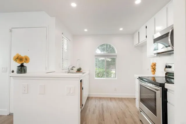 a kitchen with stainless steel appliances granite countertop a stove a sink and a microwave