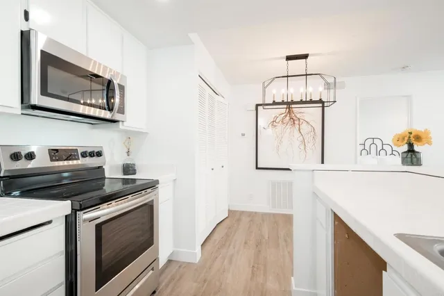 a kitchen with stainless steel appliances a stove a microwave and white cabinets