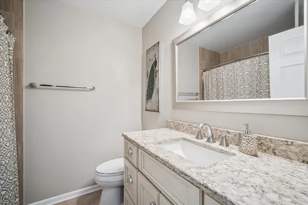 a bathroom with a granite countertop sink a toilet and a mirror