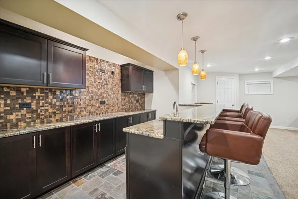a kitchen with stainless steel appliances granite countertop a stove a sink a refrigerator a dining table and chairs with wooden floor