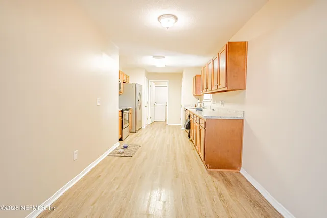 an empty room with chandelier fan and windows