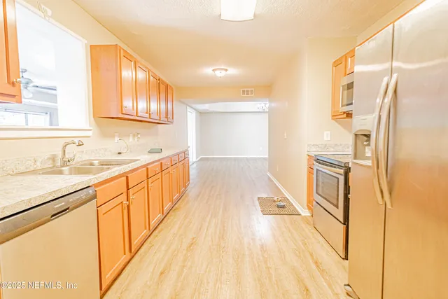 a view of an empty room with window and a kitchen
