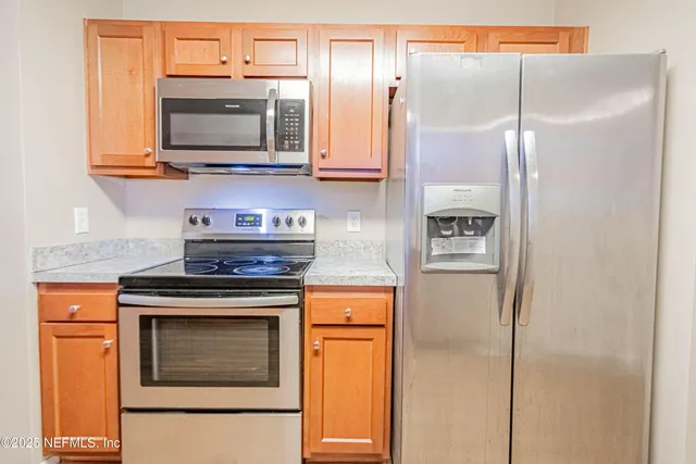 an empty room with chandelier fan and windows