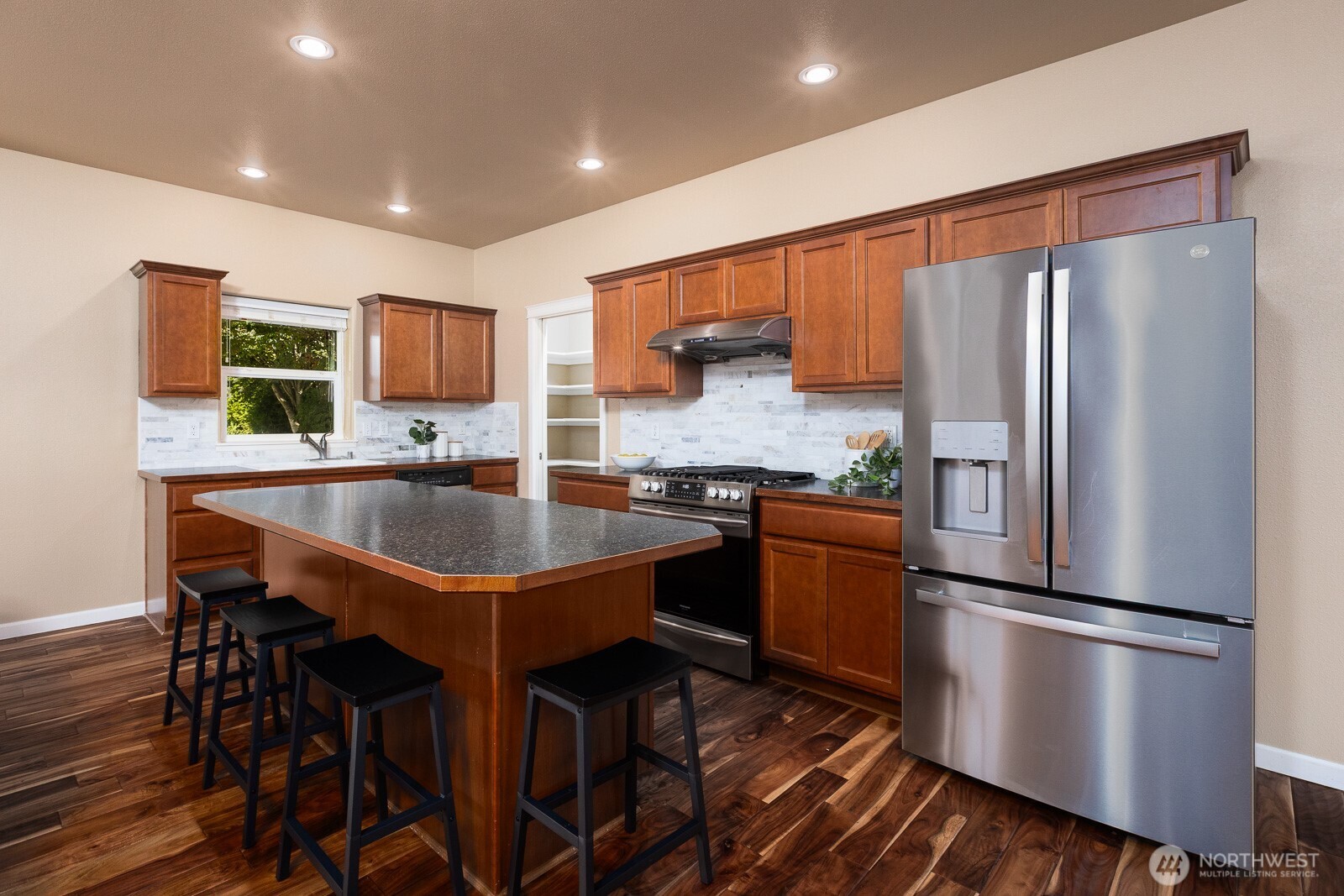 5002 70th Way Southeast Lacey, WA 98513 - Photo 6 of 40 a kitchen with stainless steel appliances granite countertop a refrigerator a stove a sink a dining table and chairs with wooden floor
