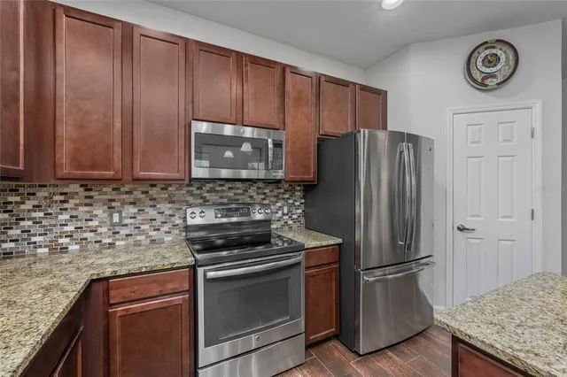 a kitchen with granite countertop stainless steel appliances and wooden cabinets