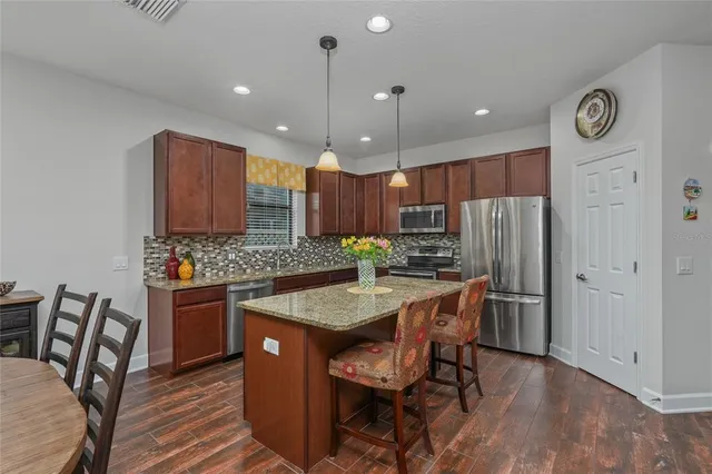 a kitchen with stainless steel appliances granite countertop a table chairs and a refrigerator