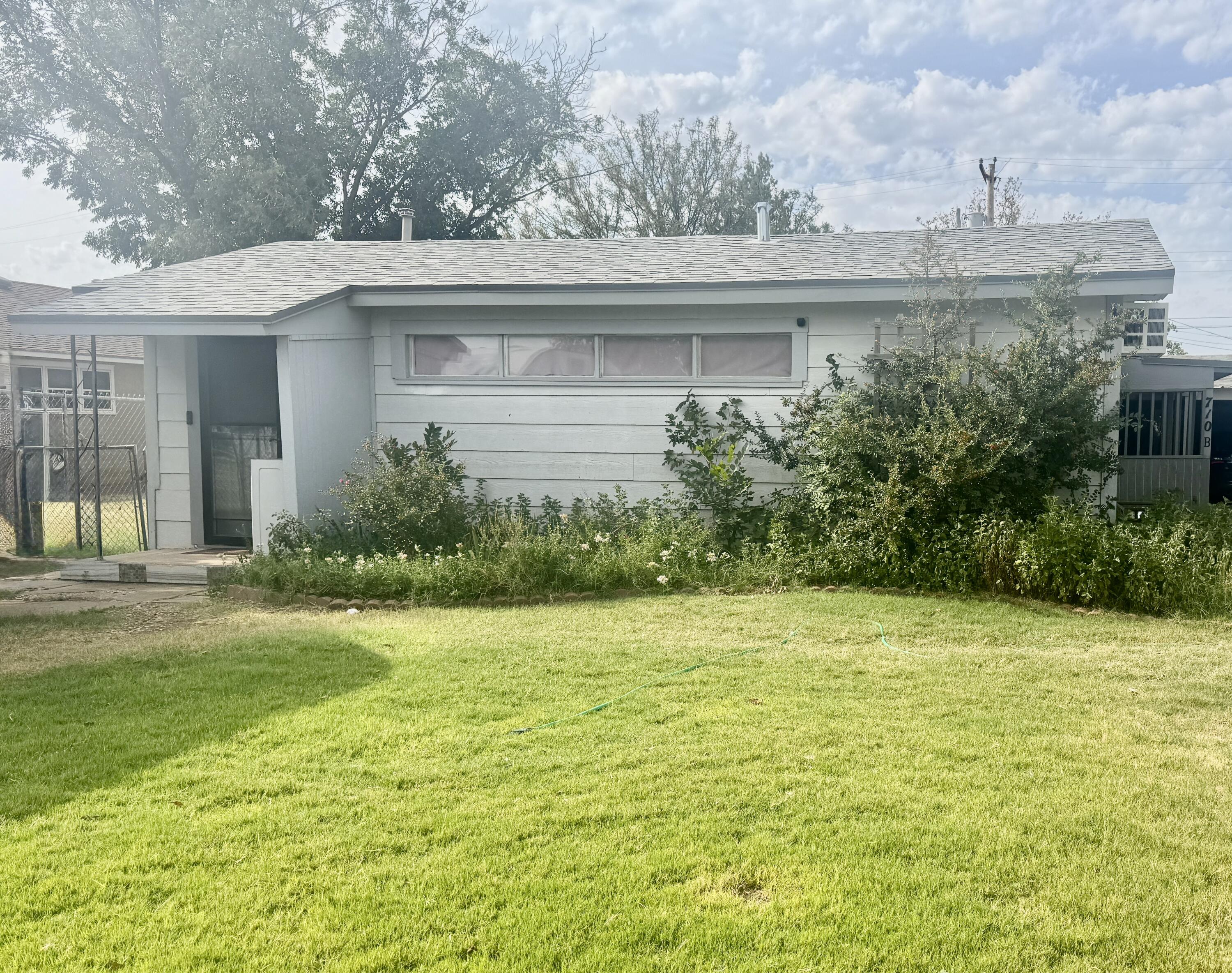 a view of a white house next to a yard with potted plants