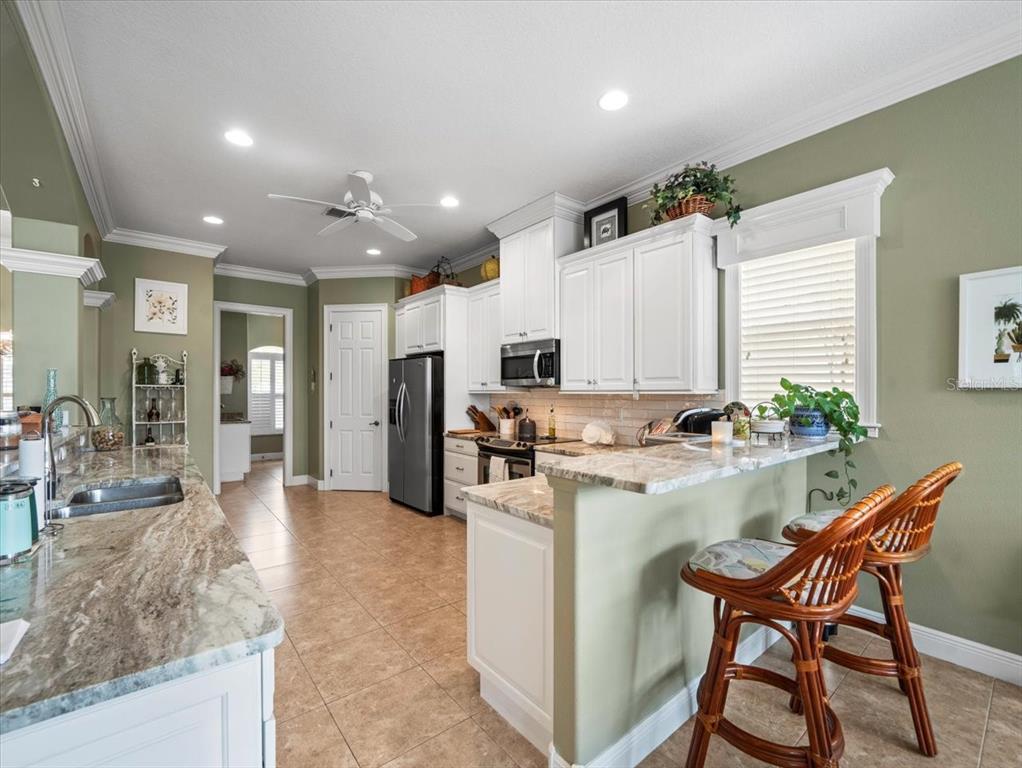8480 Athens Court Weeki Wachee, FL 34613 - Photo 14 of 60 a kitchen with stainless steel appliances granite countertop table chairs sink and cabinets