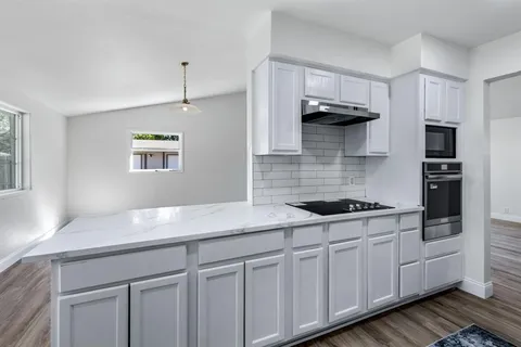 a kitchen with stainless steel appliances granite countertop a sink a stove and cabinets