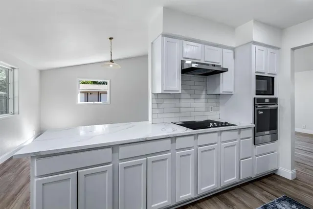 a kitchen with stainless steel appliances granite countertop a sink a stove and cabinets