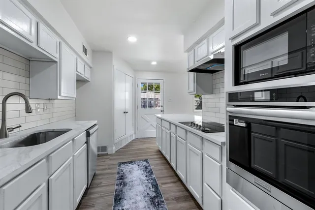 a kitchen with stainless steel appliances granite countertop a sink and stove top oven