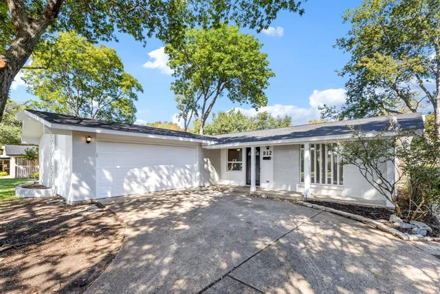 a front view of a house with a yard and potted plants