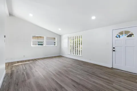 a view of an empty room with wooden floor and a window