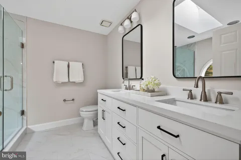 a bathroom with a double vanity sink toilet and mirror
