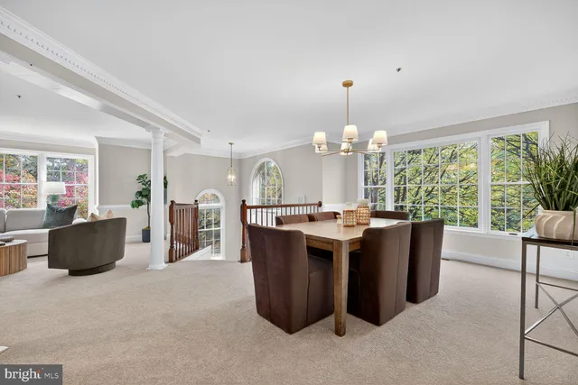 a view of a dining room with furniture a chandelier and large windows