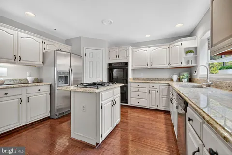a kitchen with granite countertop white cabinets and white appliances
