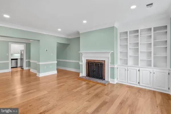 a view of an empty room with wooden floor fireplace and a window