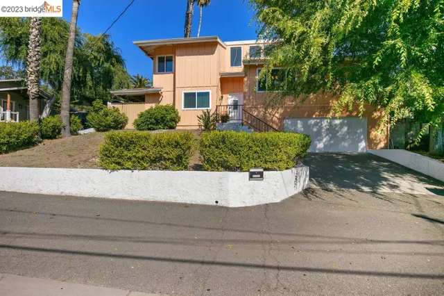 a view of a house with a yard and large tree