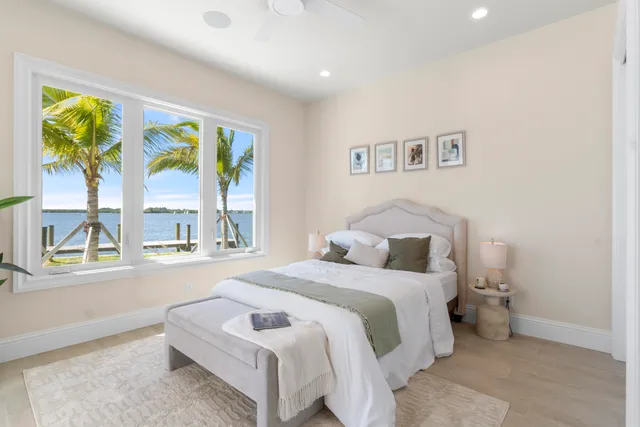 a spacious bedroom with a large bed a chandelier and windows
