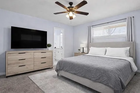 a bedroom with a bed flat screen tv and a chandelier