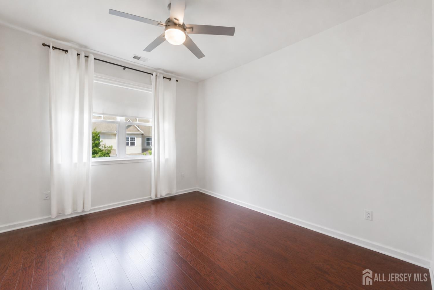 133 Savoth Lane Colonia, NJ 07067 - Photo 18 of 21 an empty room with wooden floor chandelier fan and windows