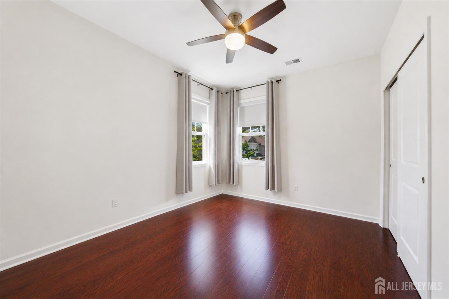 133 Savoth Lane Colonia, NJ 07067 - Photo 20 of 21 an empty room with wooden floor chandelier fan and windows