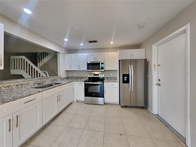 a kitchen with granite countertop a refrigerator and a sink
