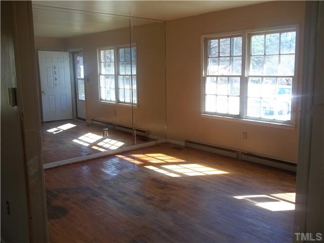 3261 Virgilina Road Roxboro, NC 27574 - Photo 3 of 9 an empty room with wooden floor and windows