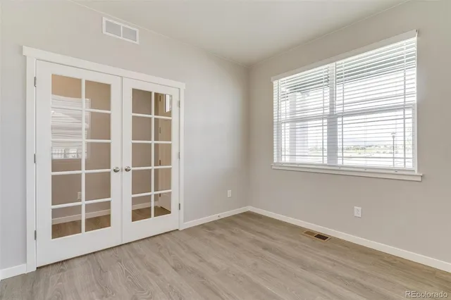 an empty room with wooden floor and windows