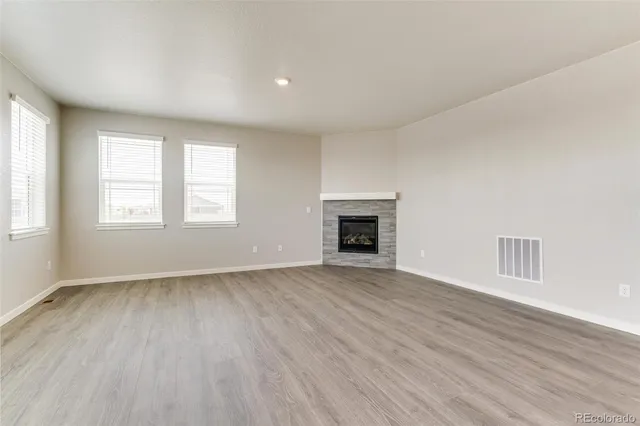an empty room with wooden floor a fireplace and windows