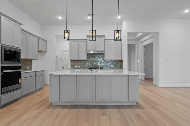 a large kitchen with cabinets wooden floor and stainless steel appliances