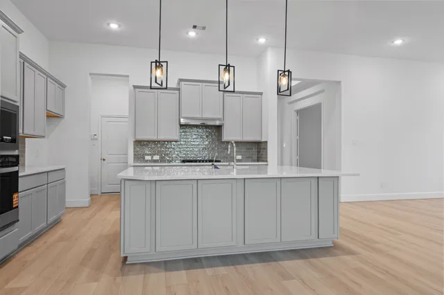 a large kitchen with kitchen island a sink stainless steel appliances and cabinets