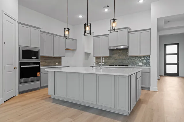 a kitchen with stainless steel appliances granite countertop a stove a sink and white cabinets