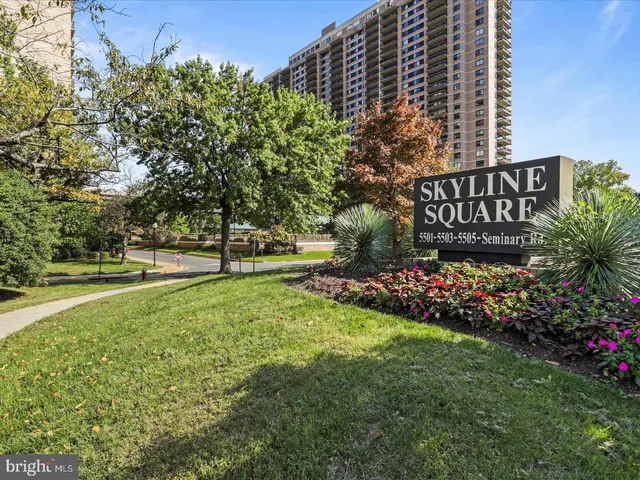 a view of a sign board with buildings in background