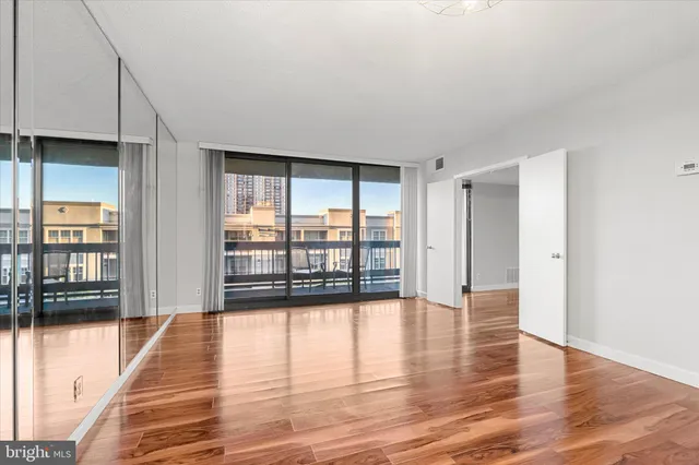 a view of empty room with wooden floor and fan