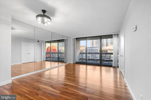 a view of empty room with wooden floor and fan