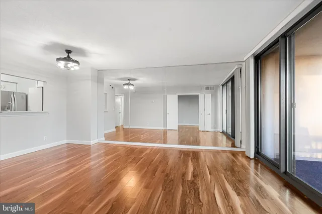 a view of empty room with wooden floor and fan