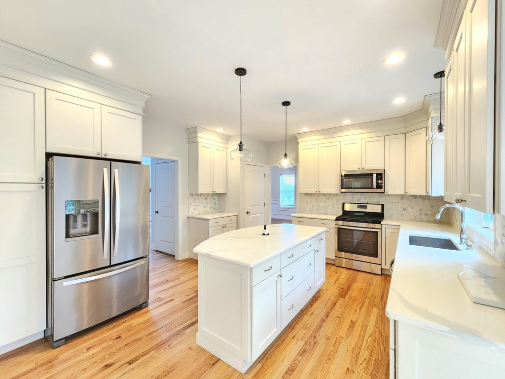 16 Exeter Road Hudson, MA 01749 - Photo 11 of 42 a large kitchen with stainless steel appliances a refrigerator a sink dishwasher a oven and a dining table with wooden floor
