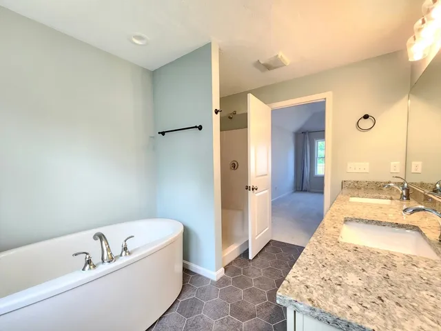 a spacious bathroom with a tub sink and mirror