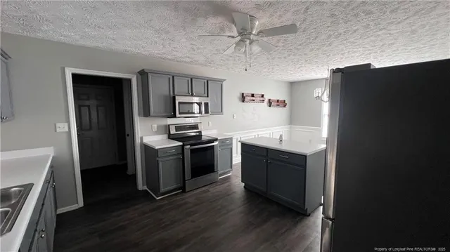 a kitchen with stainless steel appliances granite countertop a refrigerator a stove a sink dishwasher and a oven with wooden floor