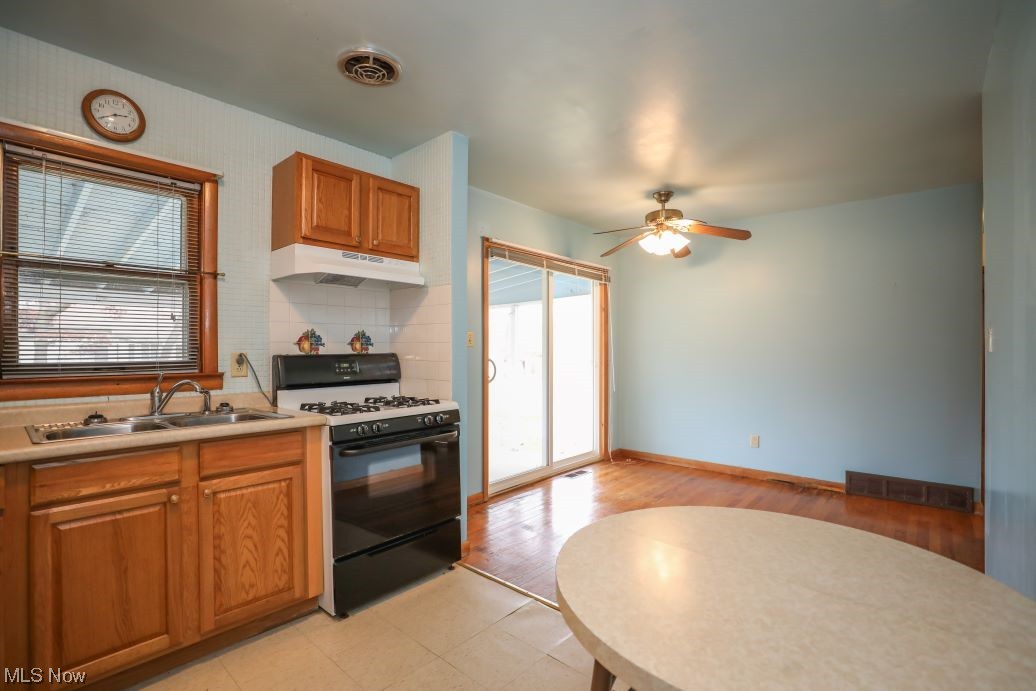 3641 Longfield Road Ravenna, OH 44266 - Photo 18 of 32 Kitchen featuring light tile floors, sink, black gas range, ceiling fan, and tasteful backsplash