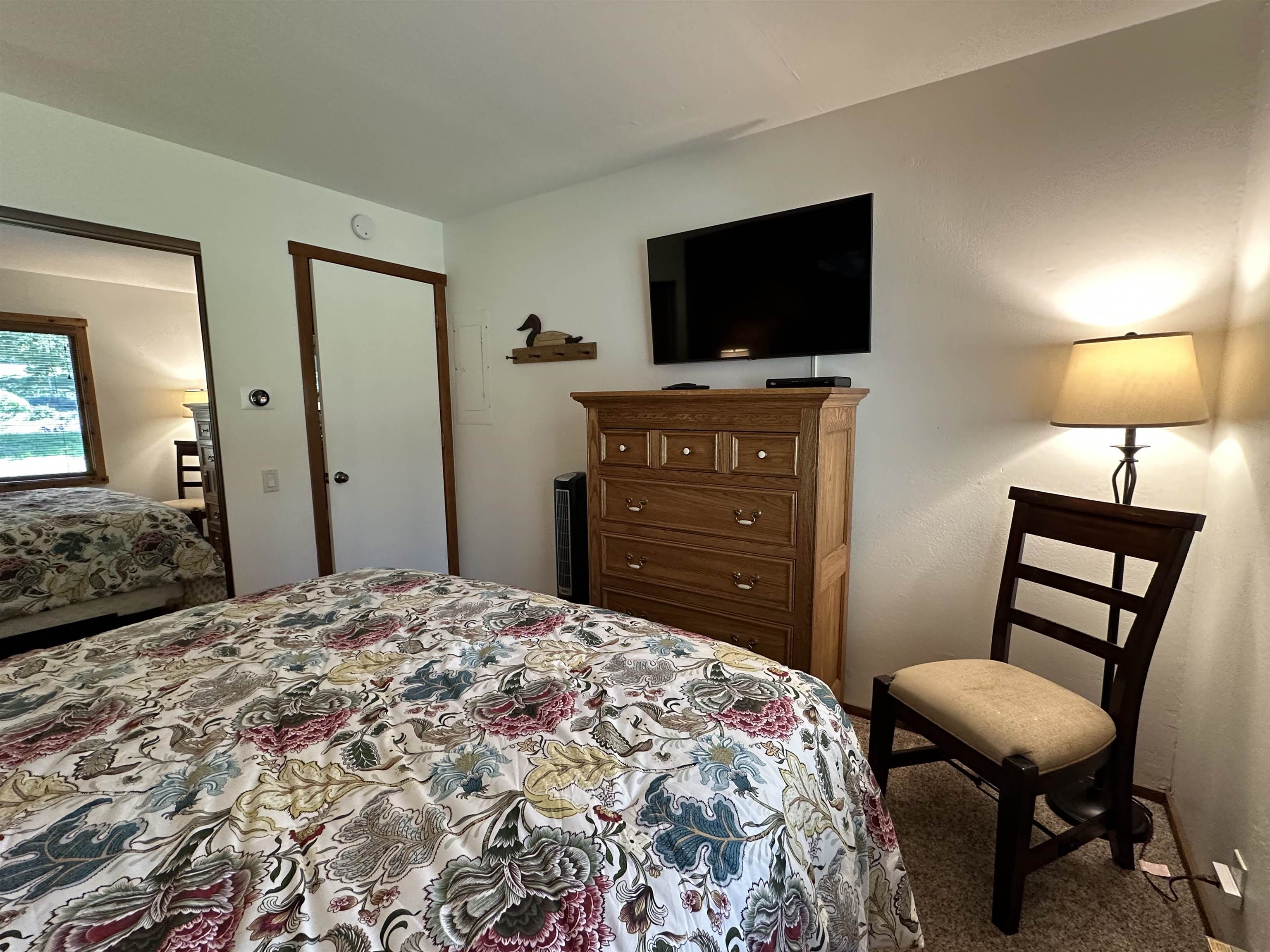315 Fascination, Unit 315 Mammoth Lakes, CA 93546 - Photo 8 of 44 Carpeted sleeping area with a mirrored closet door, a window with exterior views, and a wall-mounted thermostat