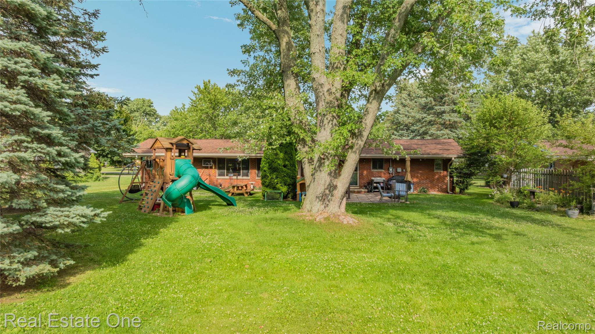 2810 Walbridge Drive Rochester, MI 48307 - Photo 57 of 58 Expansive grassy backyard featuring mature trees, a brick exterior, and a stone patio
