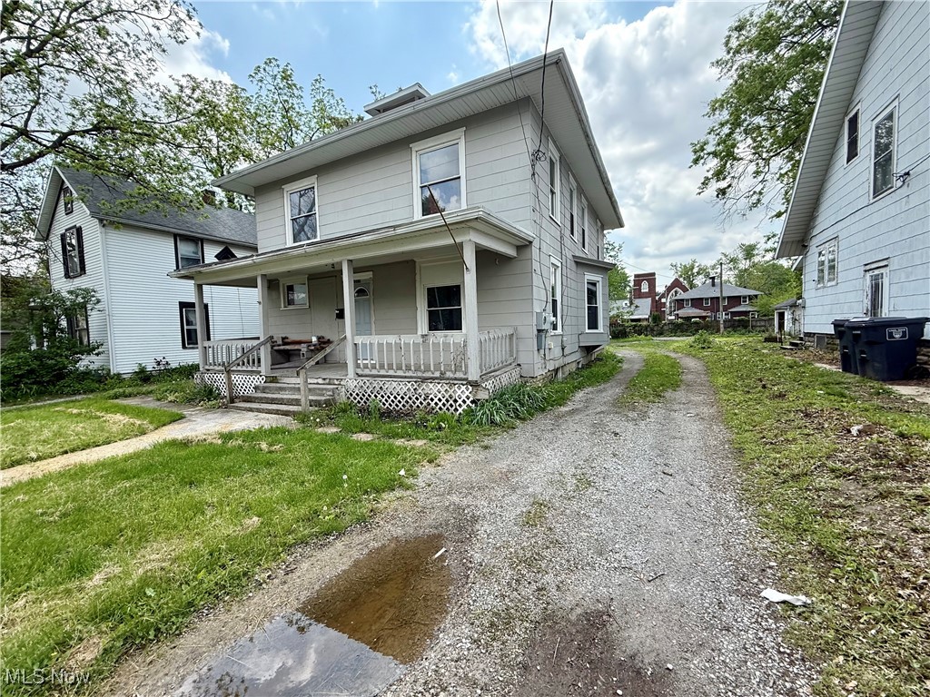 American foursquare style home featuring a porch and dirt driveway