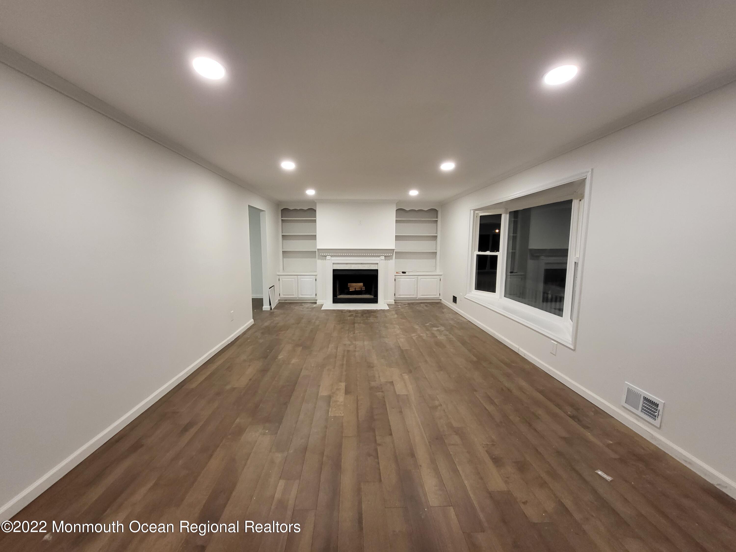 13 Spicy Pond Road Howell, NJ 07731 - Photo 3 of 7 an empty room with wooden floor and fireplace