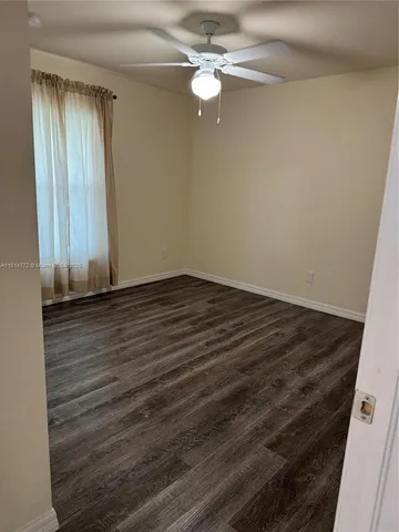 en empty room with wooden floor and fan